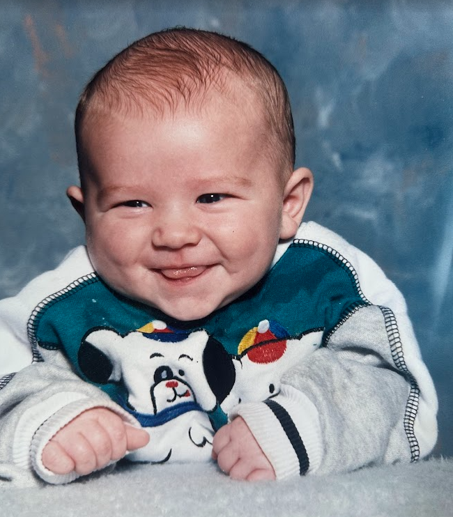 Aaron as a smiling baby in a jacket